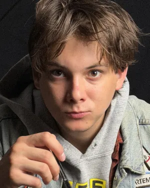 A man with short brown hair wearing a denim jacker looks forward