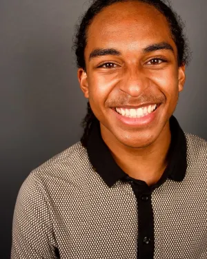 A man in a gray collared shirt smiles