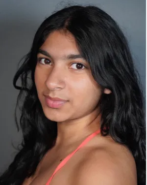 A woman with long black hair turns to face the camera