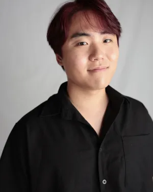 A man wearing a black collared shirt smiles