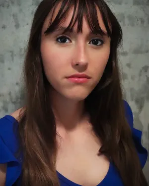 A woman with brown hair and bangs wearing a blue blouse
