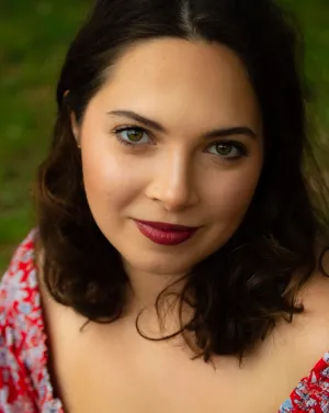A woman with brown hair wearing a red floral blouse