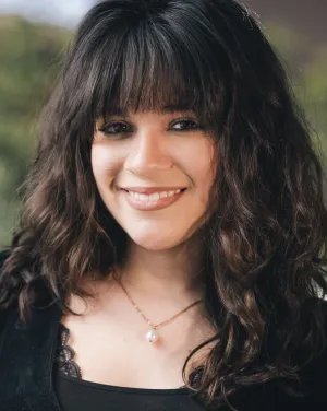 A woman with dark hair and bangs smiles