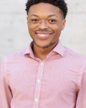 A man in a red collared shirt smiles