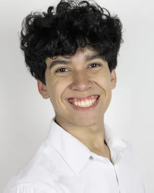 A man with brown curly hair in a white button down smiles