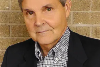 man in blue in front of brick wall 