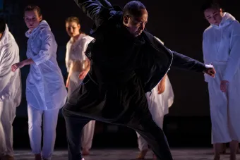 man dancing with dancing ensemble in the background