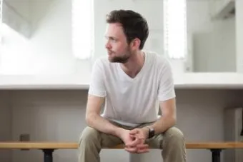 man in white sitting on a bench 