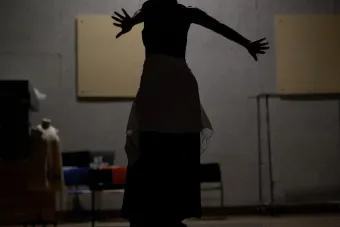 silhouette of a woman with curly hair posing with her arms stretched behind her