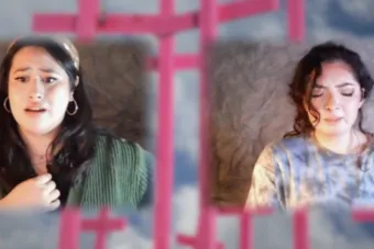 two women acting remotely through their own virtual windows with an image of pink crosses in the background