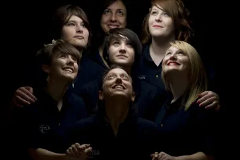 Seven women looking upward at light