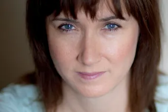 woman in blue against gray wall