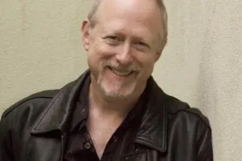 Schenkkan headshot in jacket against a wall