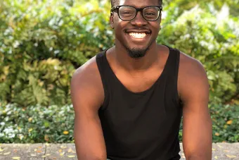 man in glasses sitting in front of a bush 
