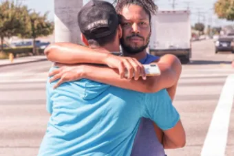 two men hugging at a cross walk 