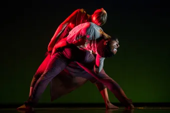 two dancers back to back in red light