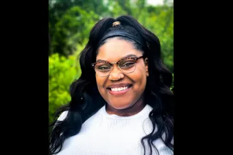woman with wavy black hair wearing a white shirt and glasses