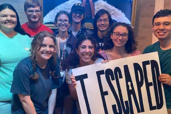 a group of students pose with a sign that says I Escaped