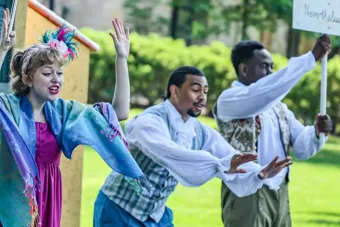 three young people in costumes performing outside