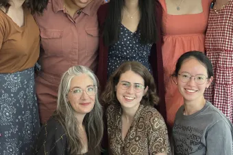 group photo of eight collaborators posing in front of a banner for SPELLS OF THE SEA