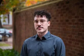 Robert Di Donato smiling at the camera in front of a brick building
