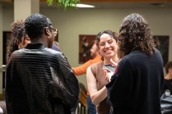 Four undergraduate students stand in the F. Loren Winship Drama Building atrium, talking and smiling