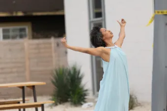 A woman in a blue dress extends her arms