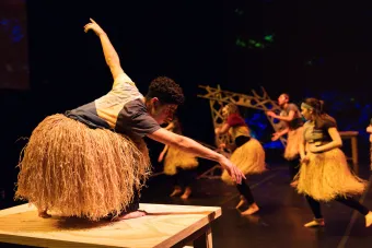 A dancer in a grass skirt extends his arms