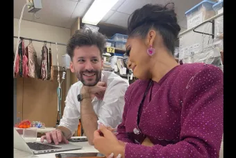 A man smiles at a woman wearing a purple costume