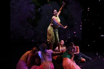 A woman wearing a green costume extends her arms
