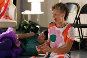 A woman with curly hair wearing a colorful shirt laughs