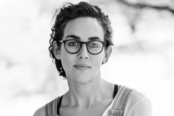 A woman with dark curly hair wearing glasses