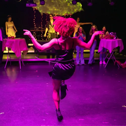 dancer in black dress under purple and yellow lighting