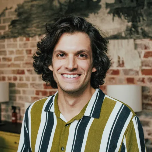 A man with brown hair and a striped shirt smiling