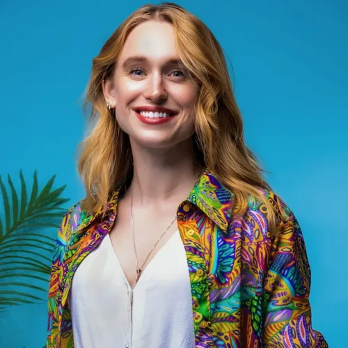 A woman with long blonde hair and wearing a tropical shirt smiles