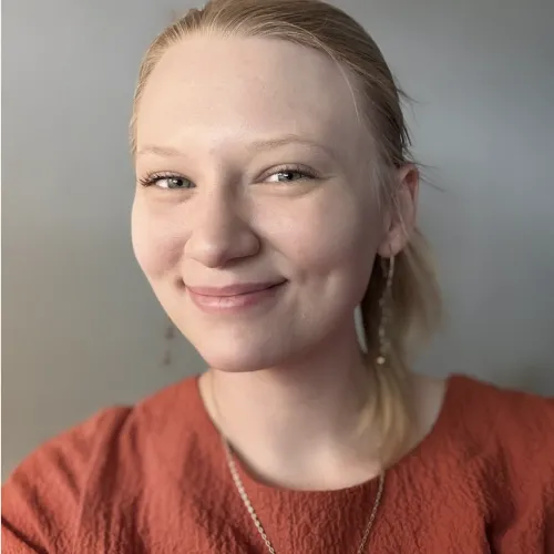 A woman wearing a ponytail and red sweater smiles