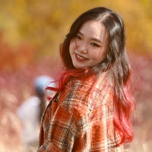 A woman wearing an orange flannel turns around and smiles