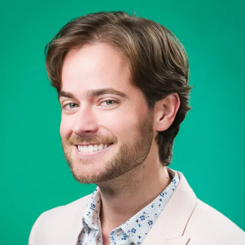 Photo of a man in a white suit jacket and green backdrop