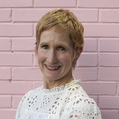 Headshot of a woman with short light red hair and a white blouse