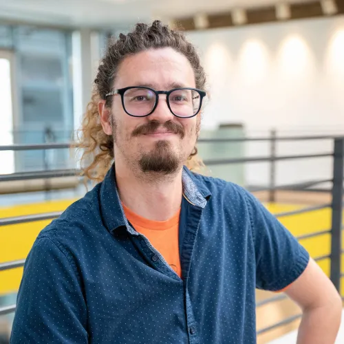 Headshot of a man in a blue buttoned down and glasses