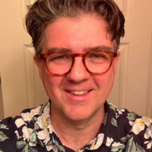 Headshot of a man in glasses and a hawaiian pattern shirt