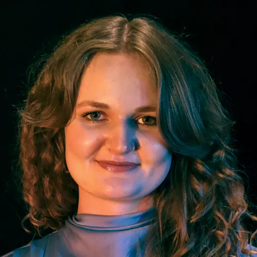 A woman with long brown curly hair smiles