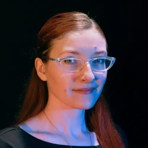 A woman with long red hair and glasses