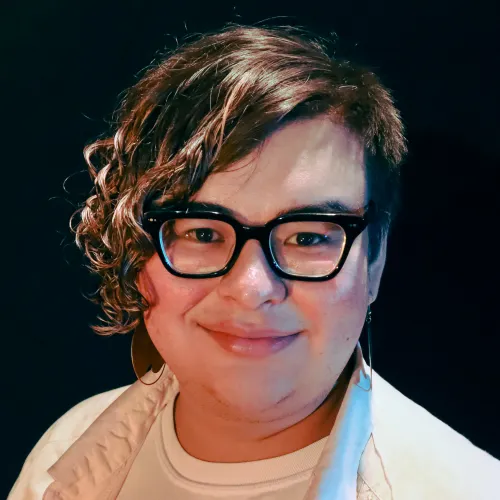 A person with short curly hair and glasses