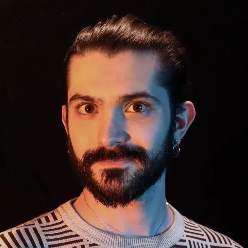 A person with long black hair pulled back and a beard