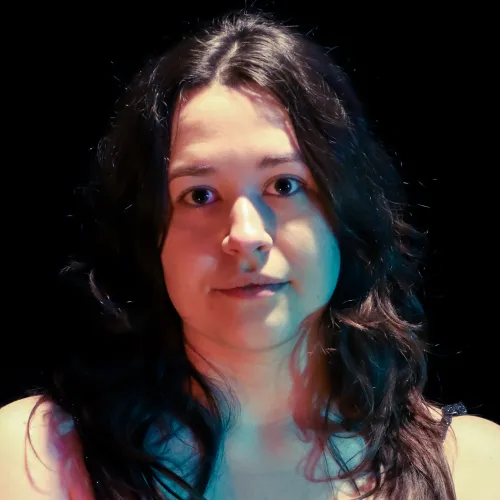 A person with long dark hair looks forward