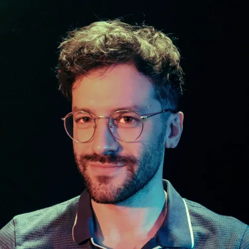 A man with short brown hair and glasses smiles