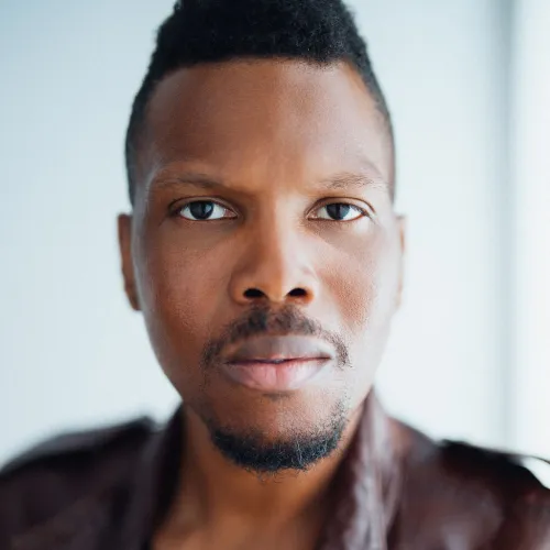 A man in a brown leather jacket looks forward