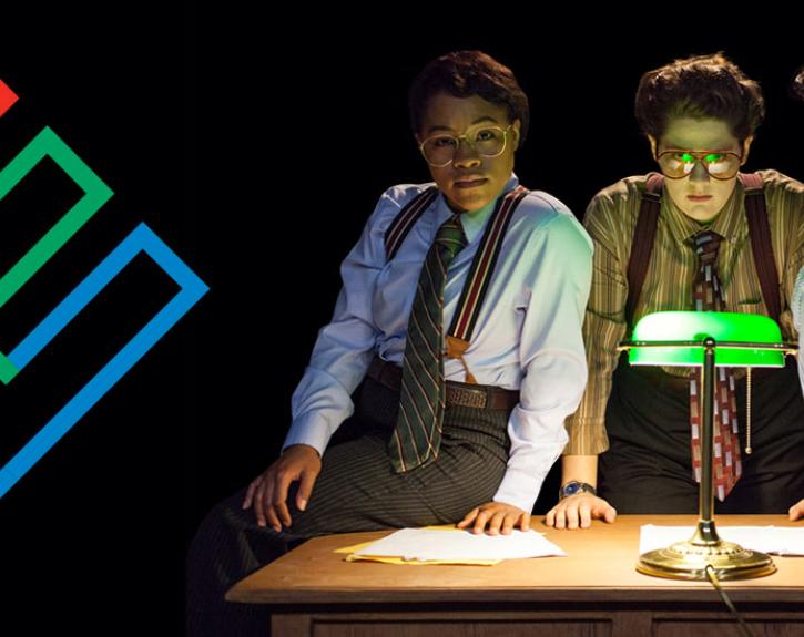 three women standing over a desk with light enron