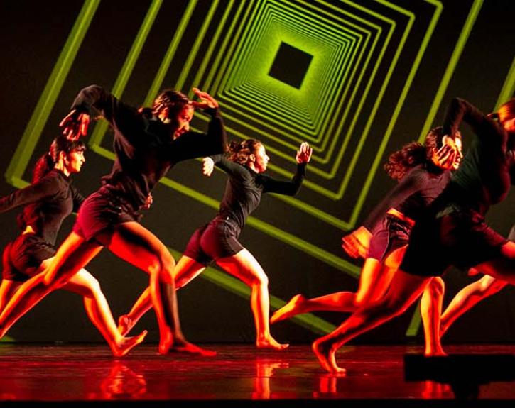 Evolution at UT Austin; dancers in right light in front of green roating box projections